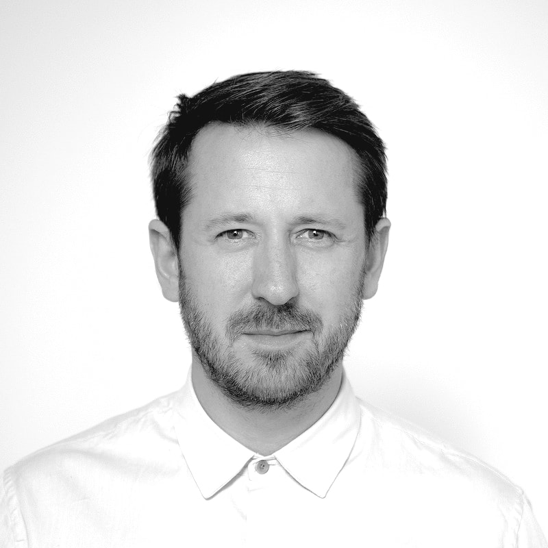 Portrait of a woman with brown hair on a flat gray background.